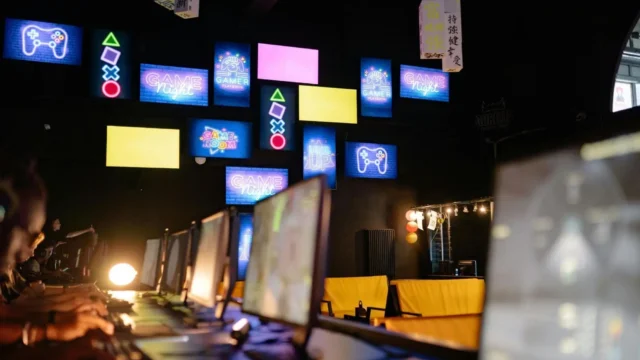 Monitores de computador sobre uma mesa em um ambiente moderno de jogos e tecnologia.